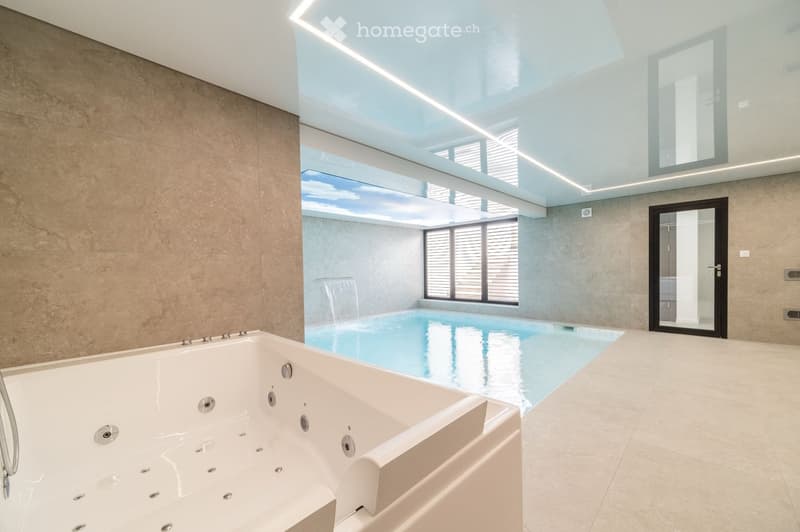 Modern bathroom with a large indoor pool, a bathtub, and large windows offering a view of the sky.