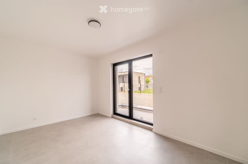 Empty room with white walls, tiled floor, and large sliding glass door leading to an outdoor area.