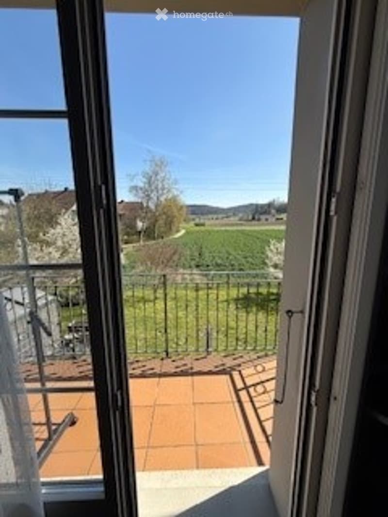 Open balcony with metal railing, tiled floor, and scenic countryside view.