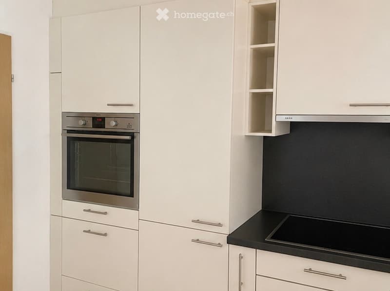 Modern kitchen with white cabinets, stainless steel oven, and black countertop.