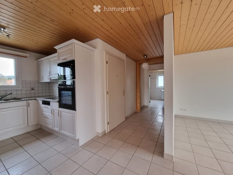Empty kitchen with white cabinets, white tile flooring, double oven, wooden ceiling, bright light, a window