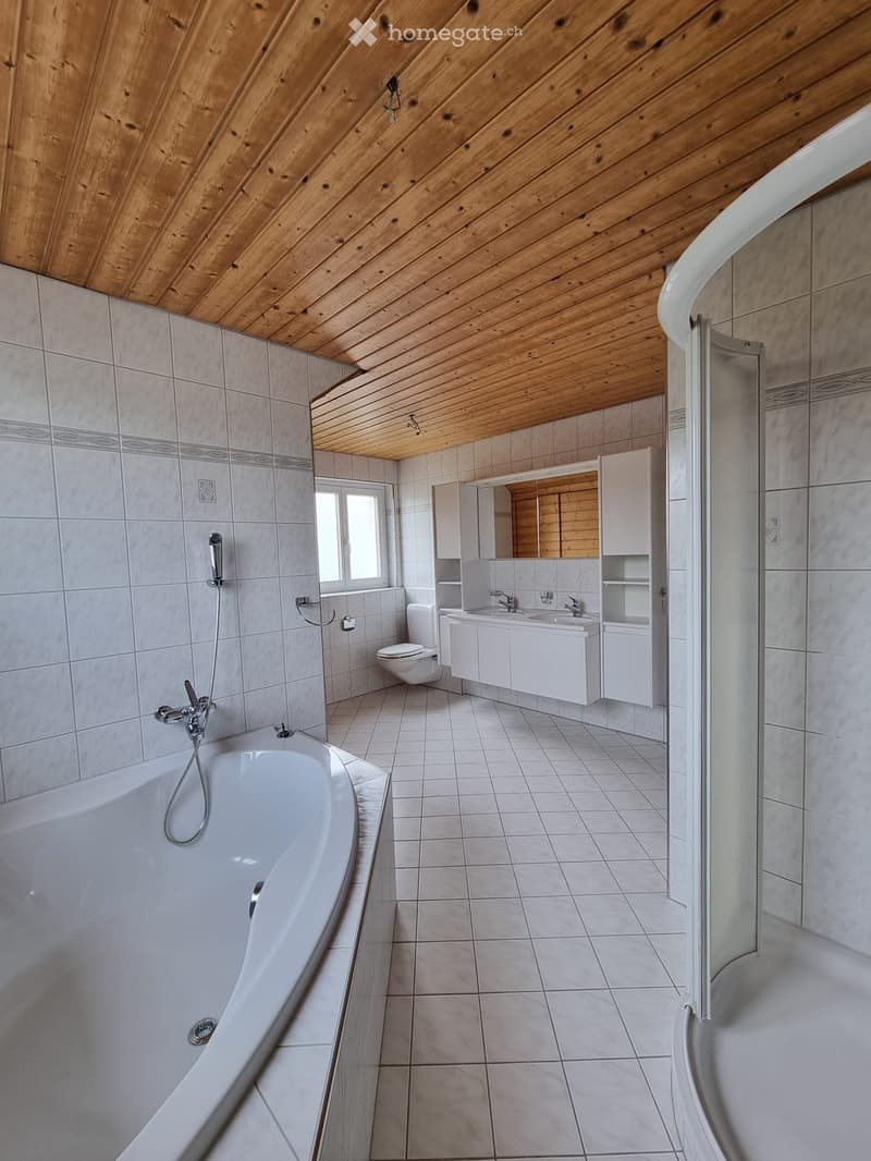 white tiled floor and walls, bathtub with shower, double sink, mirror, toilet