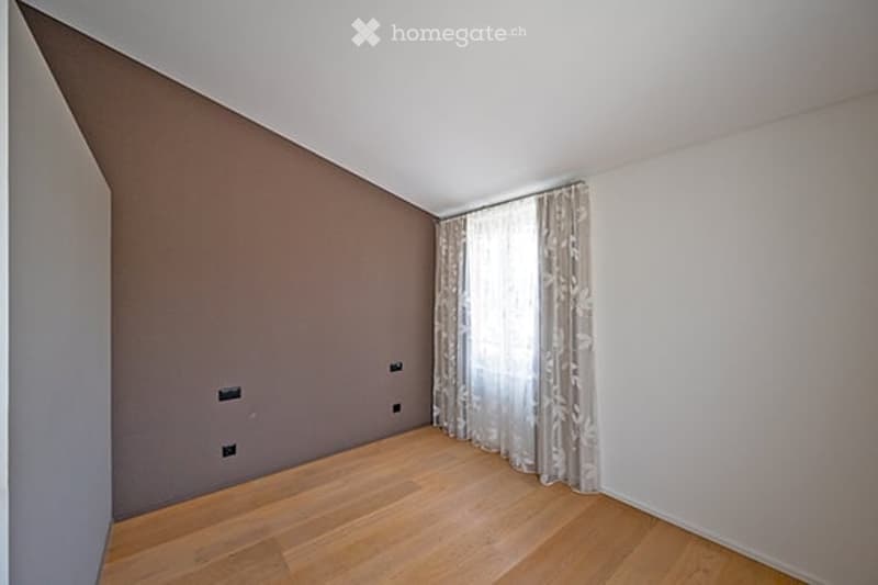 Empty room with wooden flooring, white walls, and a curtained window. No furniture or equipment present.