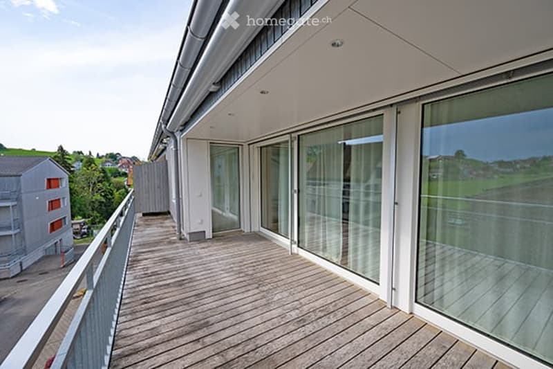Balcony with wooden decking, large glass sliding doors, and scenic view of the surrounding landscape.