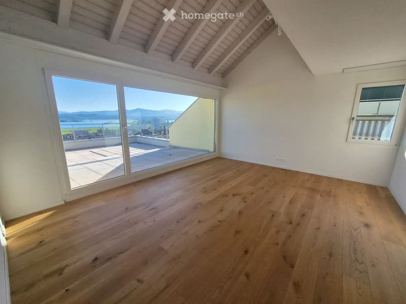 Empty room with wooden flooring, large windows, and a view of the landscape through the sliding doors.