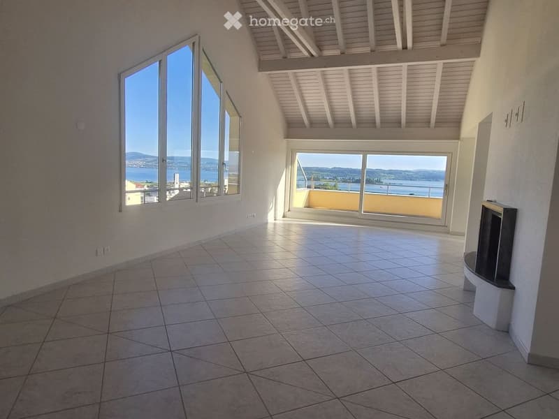 Empty room with tiled floor, large windows offering a scenic view, and a fireplace on one wall.
