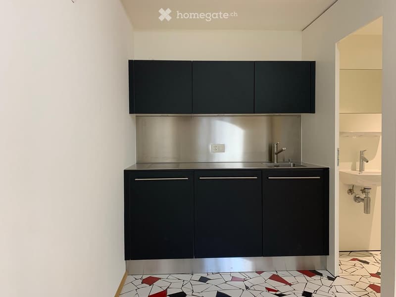 black cabinets, silver counter, sink, faucets, outlet, tile floor