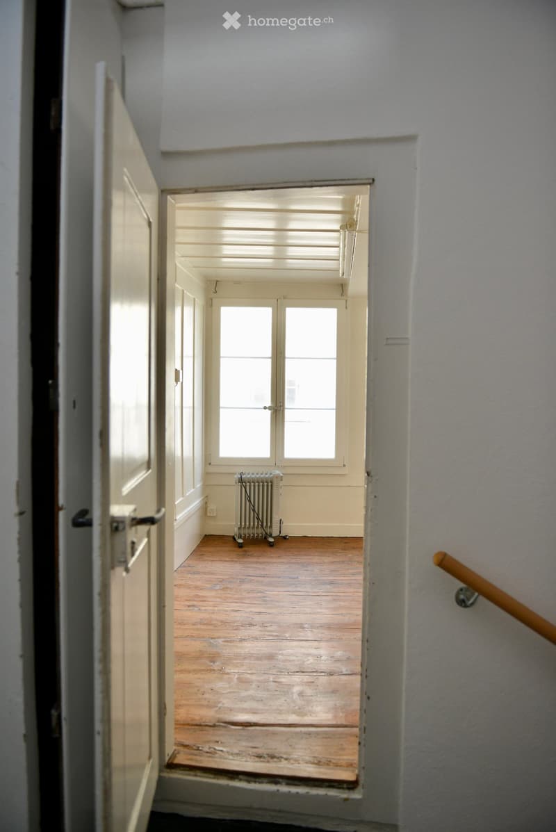 empty room, wooden floor, radiator, open door, light wall, window