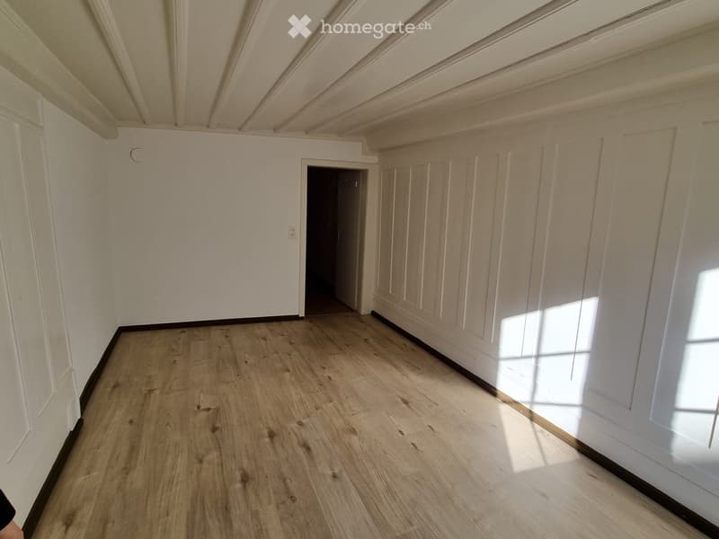 room with hardwood floors, white walls, ceiling, doorway