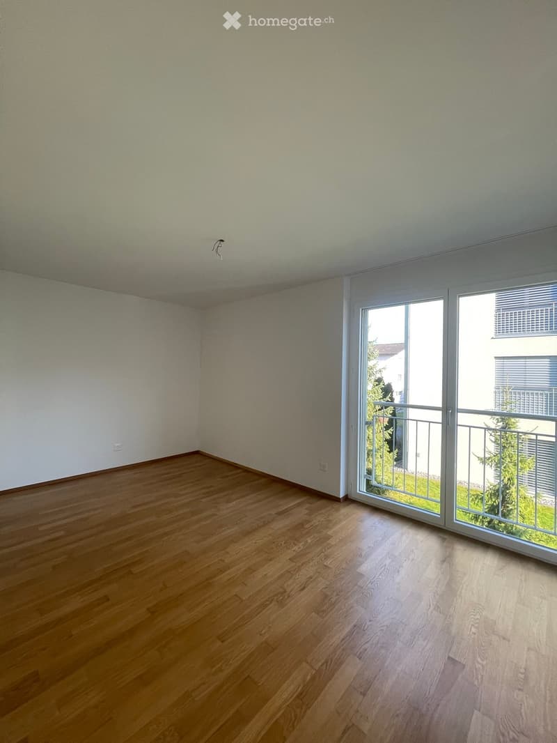 wooden floor, white walls, large sliding doors leading to balcony, power outlet on the wall