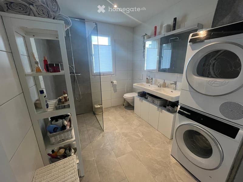 modern bathroom with shower, toilet, sink, washing machine, and storage shelves