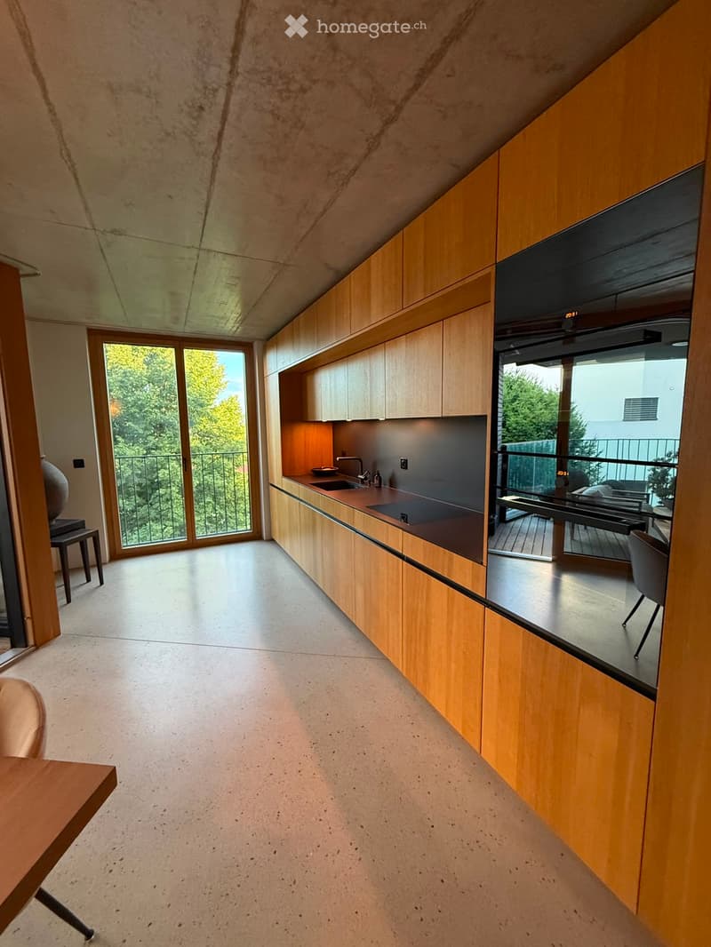 Modern kitchen with wooden cabinets, large windows, and a balcony view.
