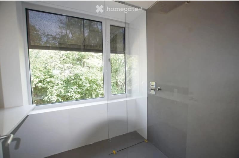 Empty room with large windows, glass sliding door, and neutral-colored walls and floor.