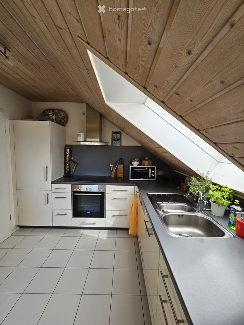 Modern kitchen with white cabinets, stainless steel appliances, and a grey countertop. Features an oven, microwave, sink, and various kitchen items.