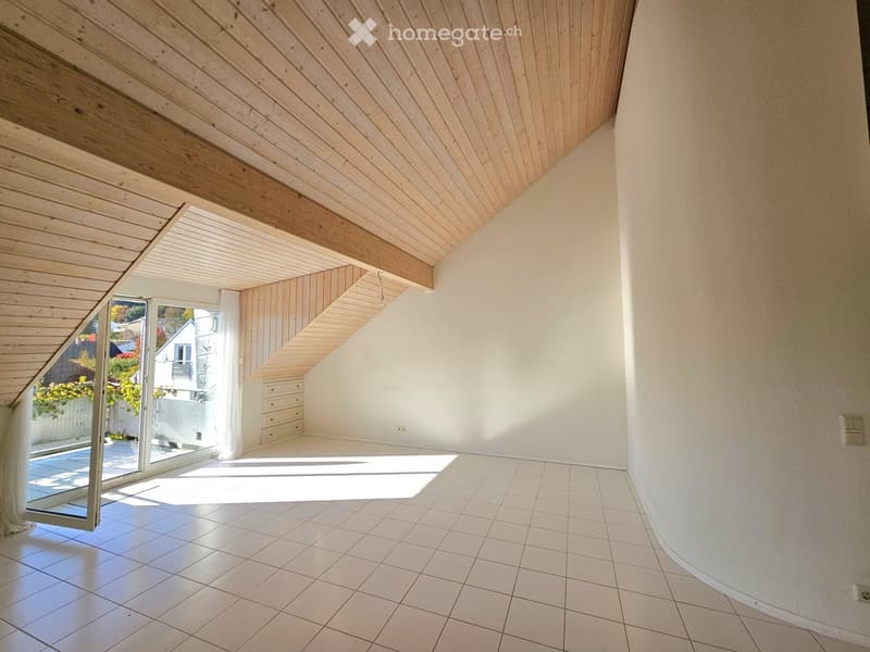 Bright, empty room with a sloped wooden ceiling, white walls, tiled floor, and large sliding glass door leading to a patio.