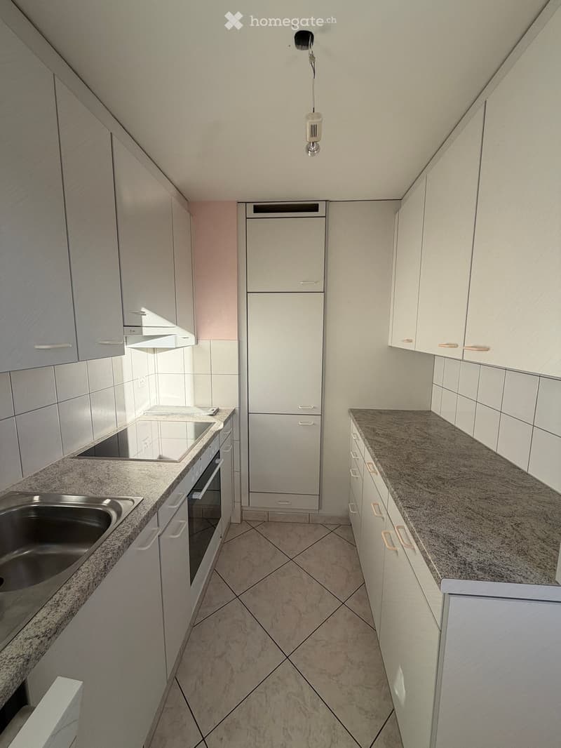 Modern kitchen with white cabinets, granite countertops, stainless steel sink, and built-in oven.