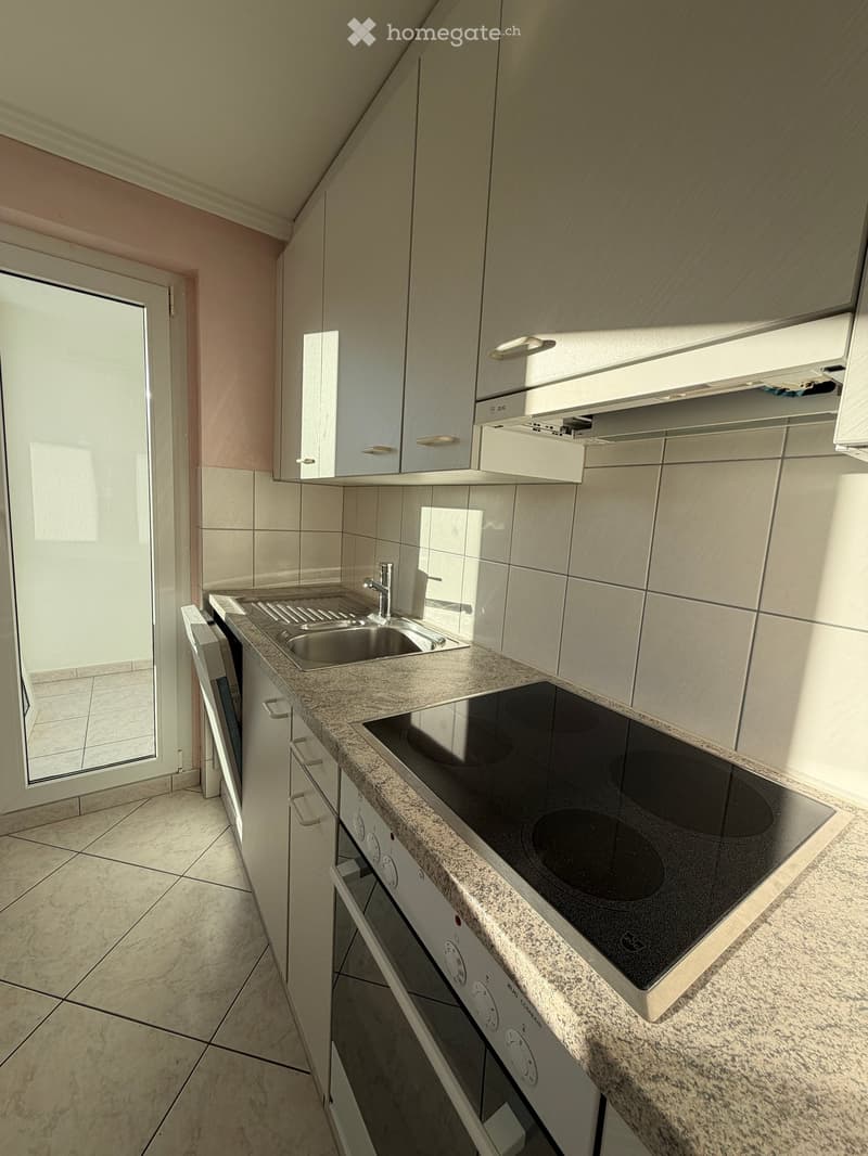 Modern kitchen with granite countertop, electric stove, sink, dishwasher, and white cabinets.
