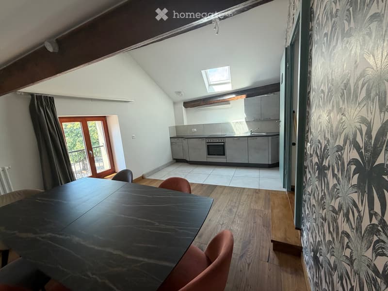 Open-plan living and dining area with wooden flooring, modern kitchen, and large windows offering a view.