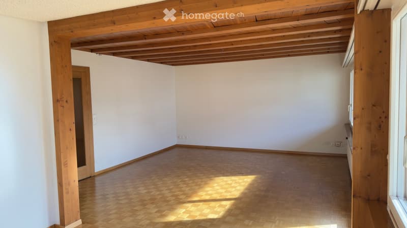 Empty room with wooden beams on ceiling and walls, wooden floor, sunlight through the window