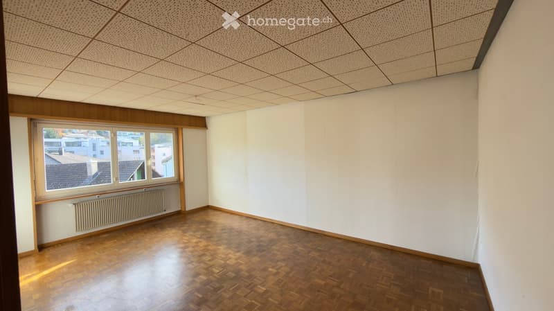 Empty room with wooden floors, white walls, and a window with a radiator below.