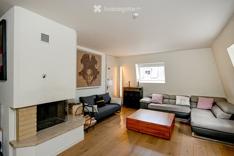 Modern living room with wooden flooring, fireplace, two sofas, coffee table, and a large window.
