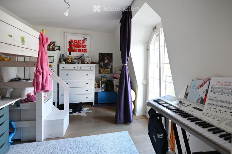A cozy, well-lit bedroom with a bunk bed, a keyboard on a stand, a curtain, and various decorative items including picture frames and shelves.