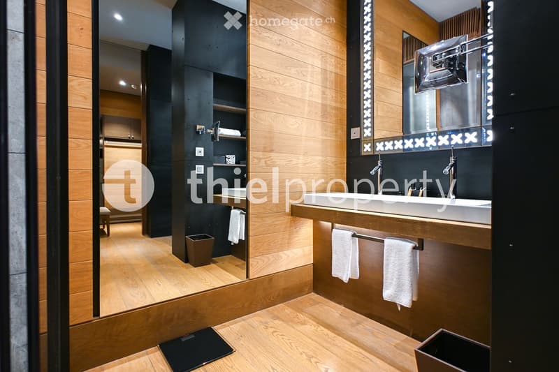 Modern bathroom with wooden accents, double sink, large mirror, and neatly arranged towels.