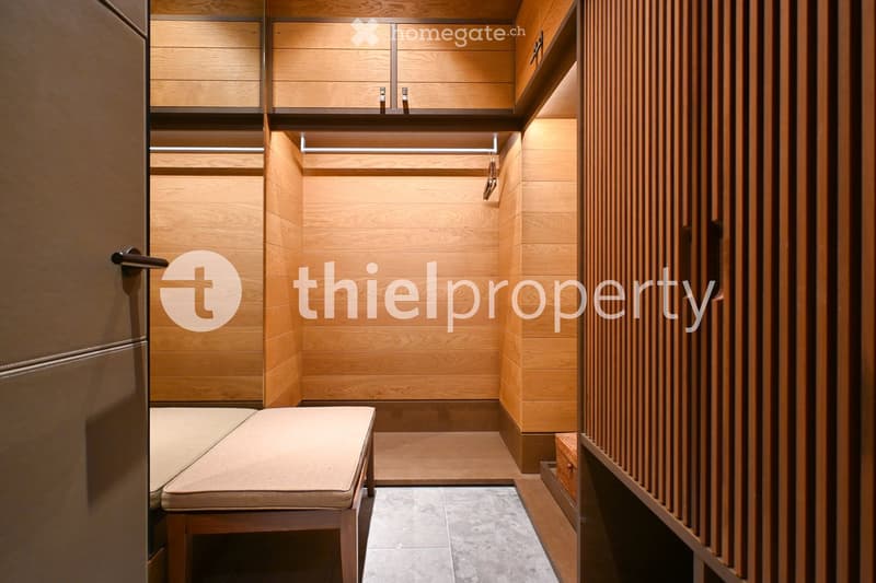 Modern, minimalist hallway with wooden walls, built-in wardrobes, and a small bench for sitting.