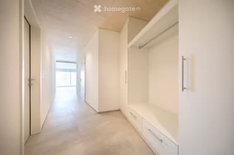 Empty hallway with white walls, built-in storage units, and a tiled floor. No furniture or personal items are present.