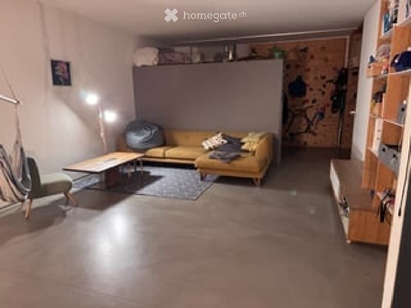 A modern living room with a yellow sofa, coffee table, wooden floor, and shelves. The room features a cozy seating area with a lamp and a small table.