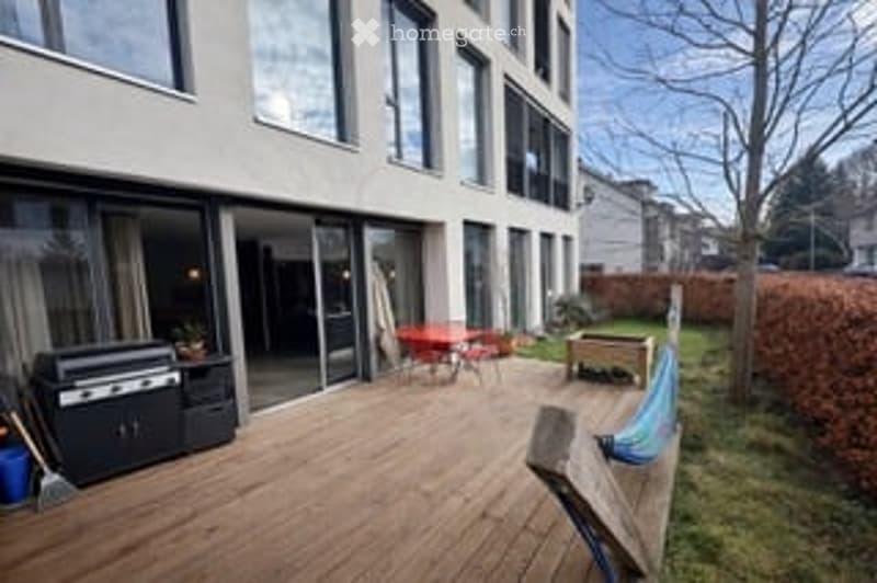 Wooden deck with outdoor furniture, grill, and a view of the surrounding area.