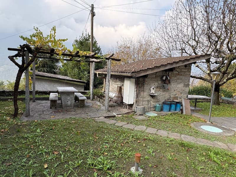 Outdoor wooden table and benches, stone walls, small shed, garden area