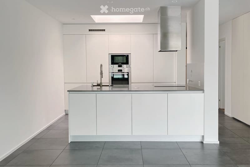 Modern kitchen with white cabinets, stainless steel appliances, and a central island with a black countertop.