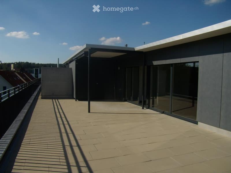 Modern balcony with tiled floor, large glass sliding doors, and a sleek, contemporary design.