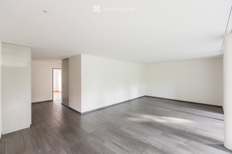 Empty room with white walls, grey tiled floor, and a doorway leading to another space.