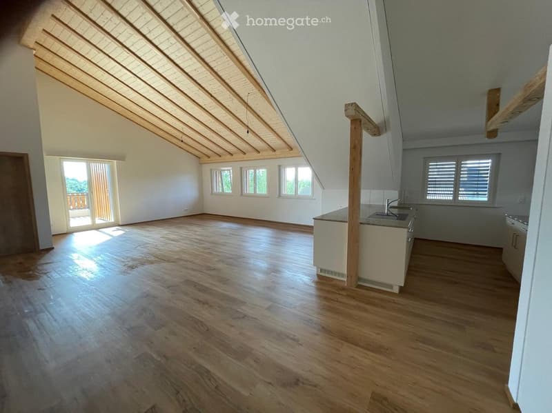 Bright, open kitchen with wooden floors, exposed wooden beams, and large windows. Features a kitchen cabinet and sink.