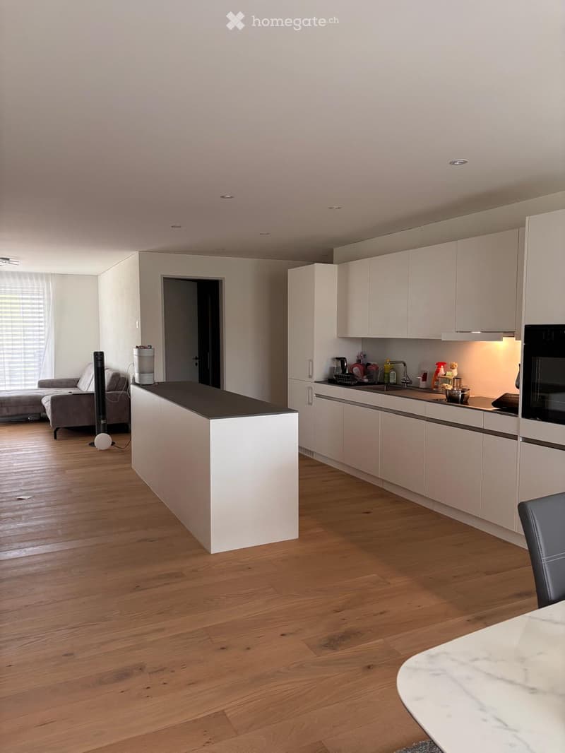 Modern kitchen with white cabinets, a central island, and a living area with a sofa and coffee table.