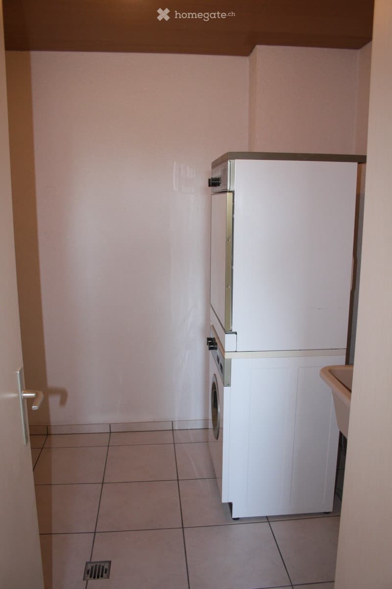 Small bathroom with tiled floor, white walls, a washing machine, and a sink.