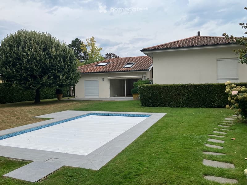 Two-story house with a tiled roof, large windows, and a modern swimming pool in the front yard.