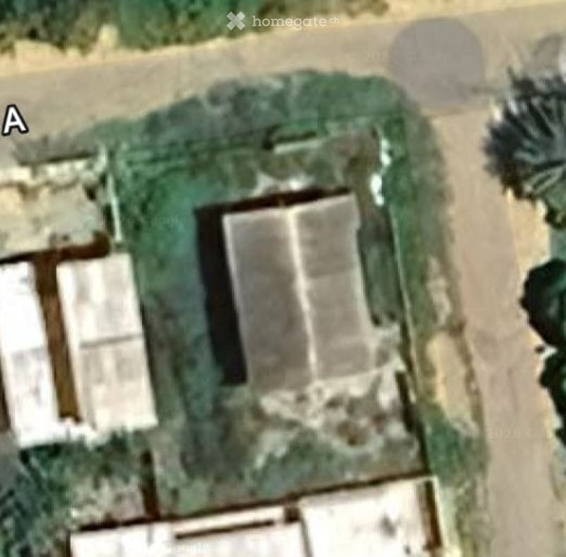 Aerial view of a residential property with a main house, two smaller outbuildings, and a landscaped garden area.