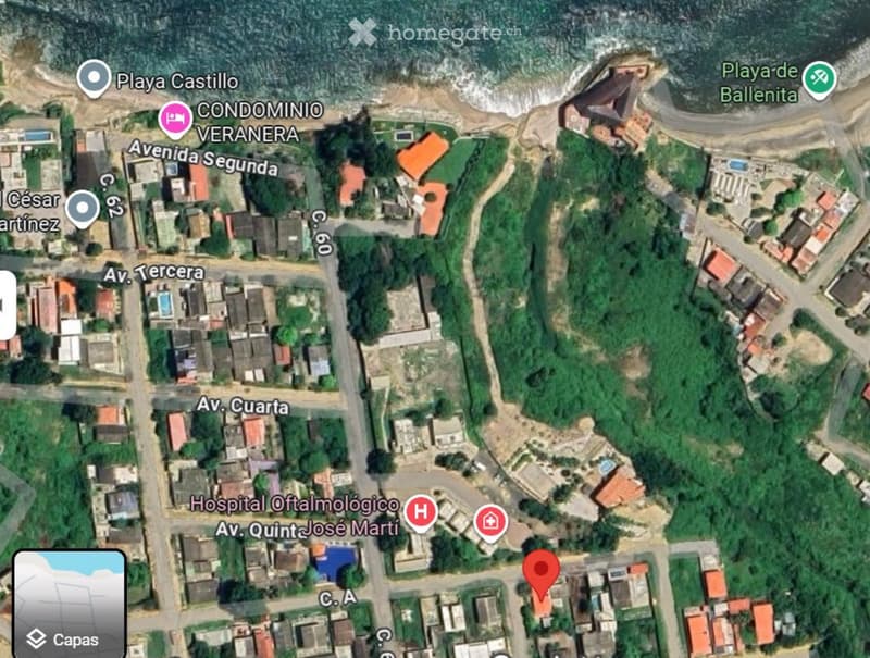 Aerial view of a residential area with multiple buildings, roads, and nearby beaches.