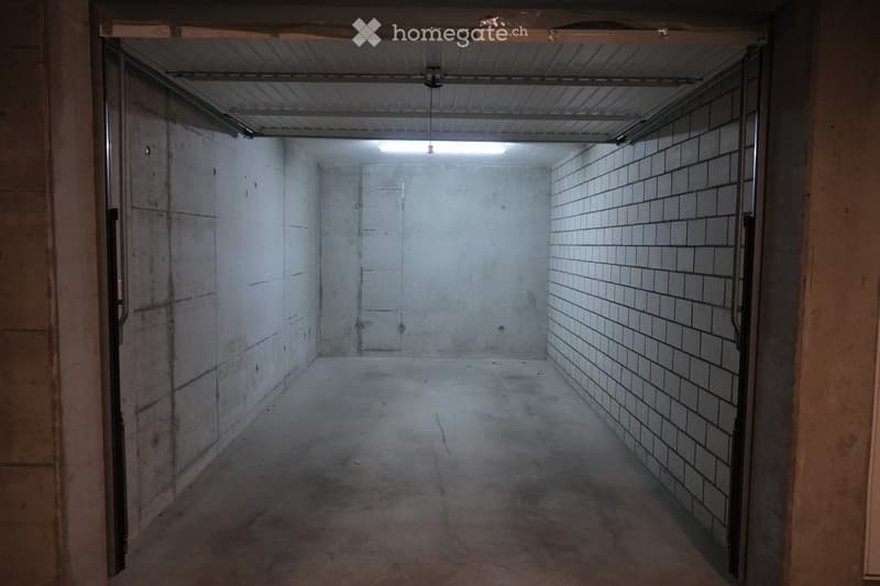 Empty garage with concrete floor, metal ceiling, and tiled wall. No furniture or equipment present.