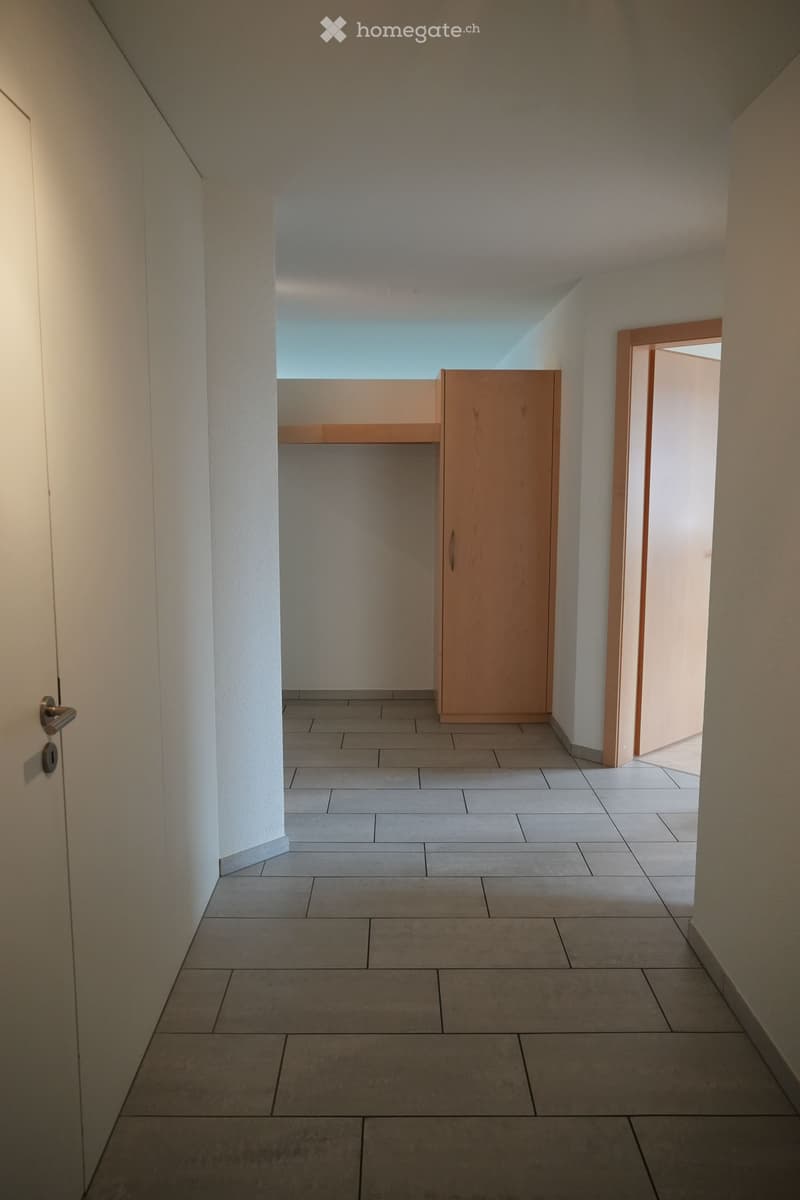 Minimalist, unfurnished room with light-colored walls, a skylight window, and a small wooden cabinet. The space is clean and empty, with a smooth floor and modern design.