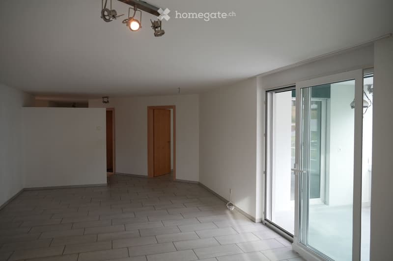 Empty room with tiled floor, white walls, and large glass sliding doors leading to a balcony. No furniture or equipment visible.