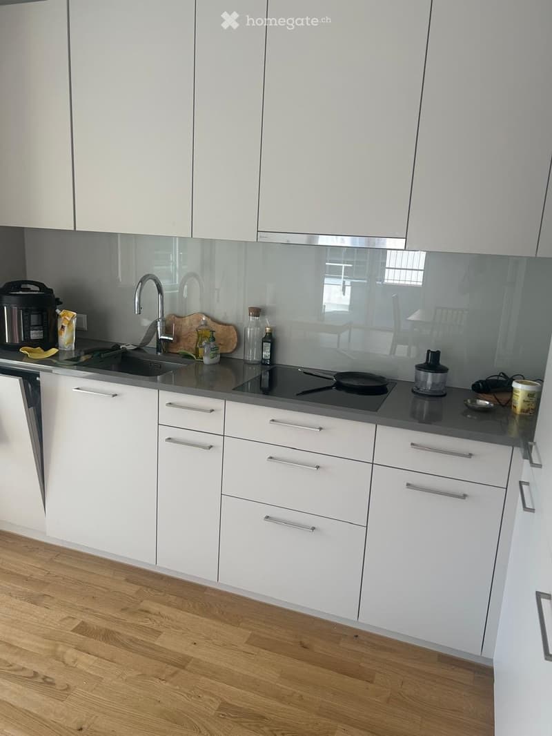 Modern kitchen with white cabinets, stainless steel sink, and various appliances on the counter.