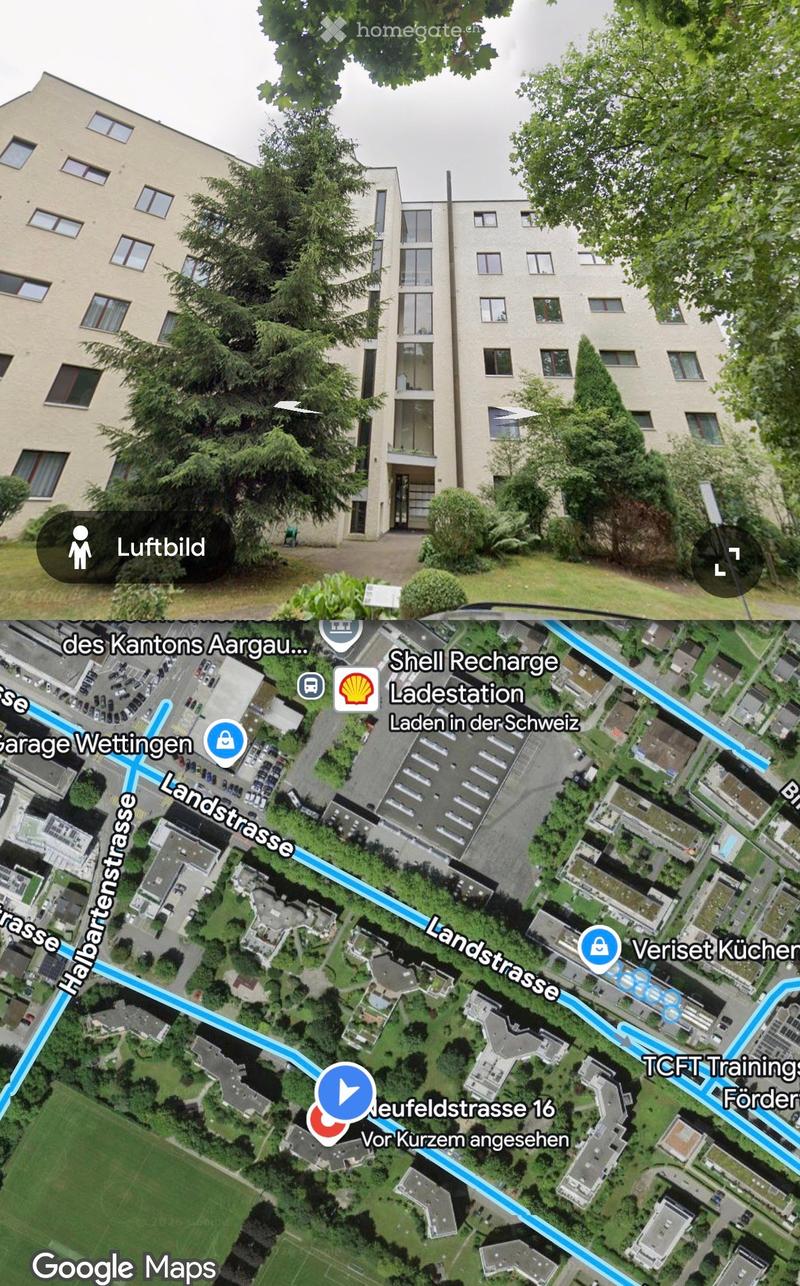 A multi-story residential building with light-colored walls and numerous windows, surrounded by trees and greenery. The building appears to be part of an apartment complex.