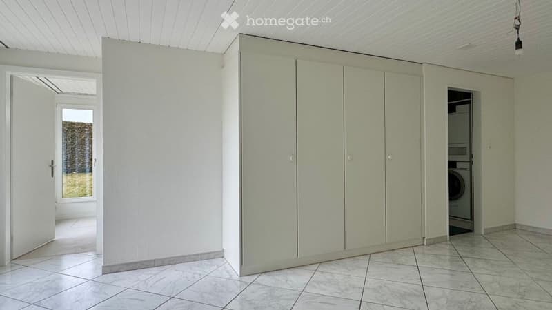 empty room with tiled floor, white walls, three closets, washer