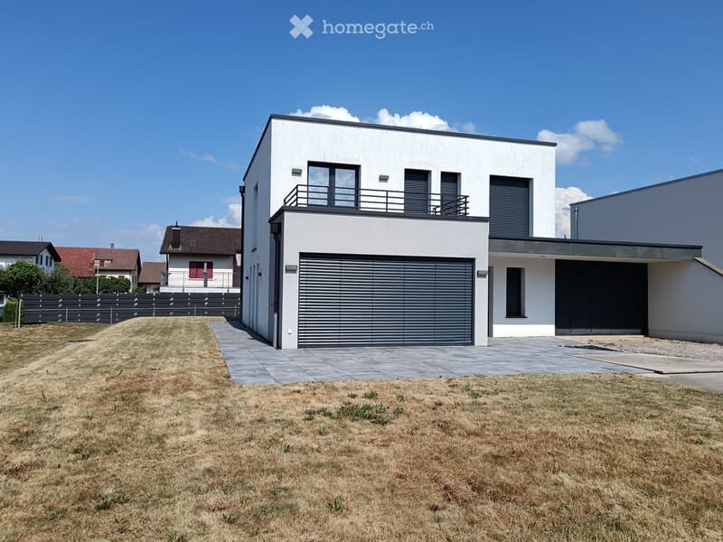 Modern two-story house with white exterior, garage, balcony, and contemporary design.