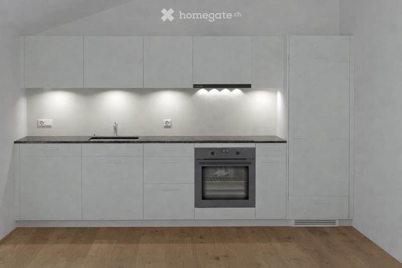 Modern kitchen with white cabinets, a sink, and an oven, featuring sleek design and built-in lighting.