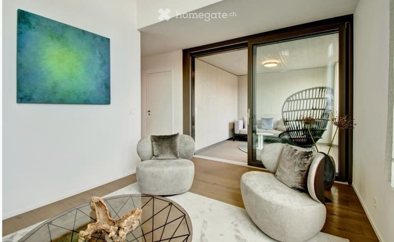 Modern living room with light-colored furniture, a glass coffee table, and a large abstract painting on the wall. The room features a sliding glass door leading to another space with additional seating.